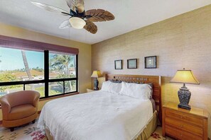 A hotel room with a bed, a chair, a nightstand, a lamp, and a ceiling fan. - New Tropical Waikoloa Base Near Sand and Golf (Waikoloa)