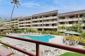 Ein Hotel mit Schwimmbad, mehreren Balkonen und Sitzbereichen im Freien.