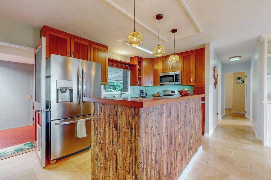 Una cucina moderna con mobili in legno, elettrodomestici in acciaio inossidabile e illuminazione a sospensione.
