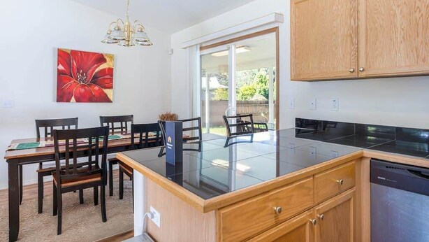Uma cozinha moderna com bancada preta, armários de madeira e um espaço de refeições com cadeiras e mesa.