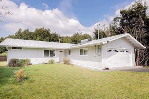 Ein eingeschossiges Haus mit Garage, Garten und blauem Himmel.