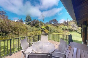A wooden deck with outdoor furniture, a railing, and a view of a hilly landscape. - New Fall $pecial Nearly Two Rainforest Acres by Volcanoes National Park (Volcano)