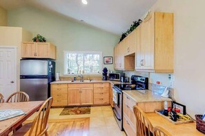 Eine Küche mit Holzausstattung, einem Kühlschrank, einer Mikrowelle und einem Spülbecken.