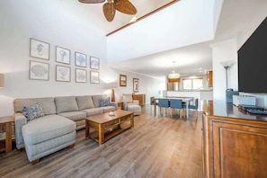 Ein geräumiges Wohnzimmer mit einer Couch, einem Couchtisch und Kunstwerken an den Wänden.