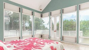 Ein Schlafzimmer mit Bett, großen Fenstern und einem Balkon.