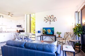 Ein modernes Wohnzimmer mit einem blauen Sofa, einem Fernseher und einer Wanddekoration.