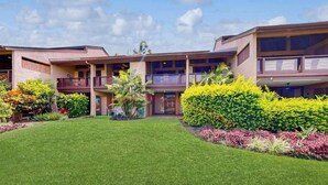 Ein mehrstöckiges Hotel mit Innenhof, Balkonen und gepflegter Bepflanzung.
