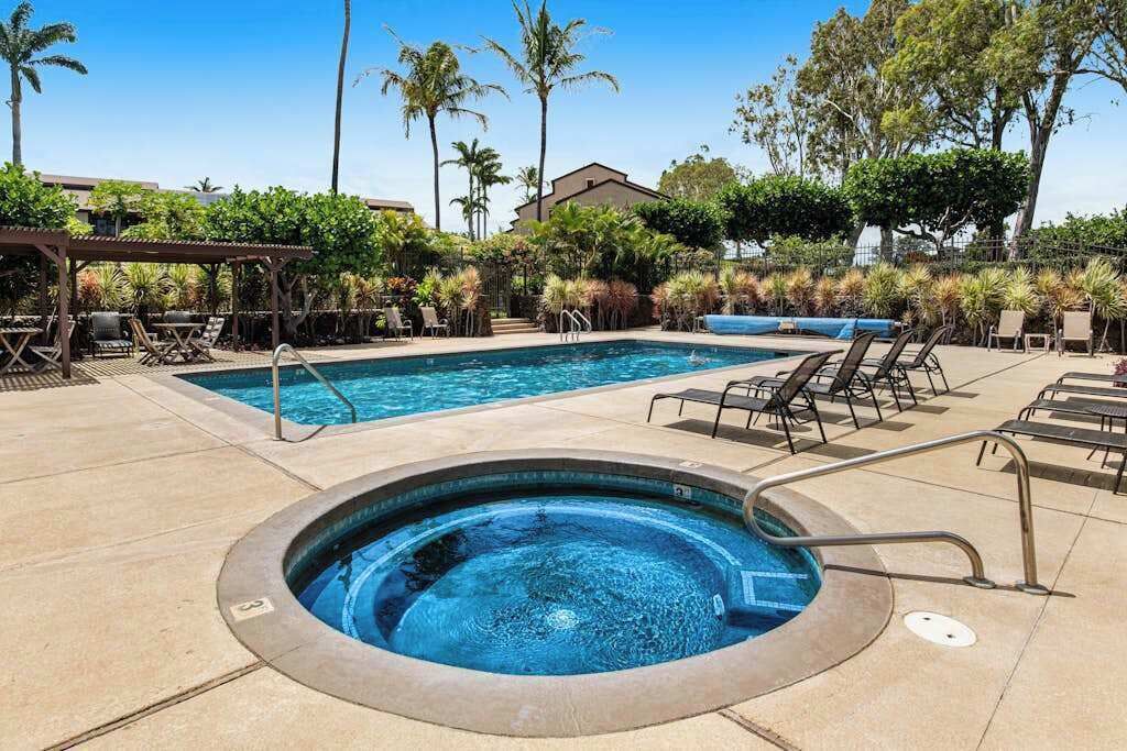 A swimming pool with lounge chairs and a hot tub.