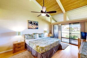 A bedroom with a bed, a ceiling fan, a painting, a nightstand, a TV, and a view of the outside.