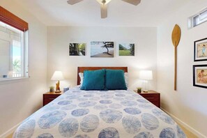 A bedroom with a bed, two bedside tables, a ceiling fan, and wall-mounted artwork. - Waikoloa Beach/Golf Resort Villa- Pool, Hot Tub, AC, Kitchen, Walk to Shops/Dine (Waikoloa)