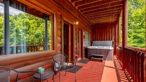 Un espacio al aire libre techado con un jacuzzi, asientos y vistas a la vegetación.