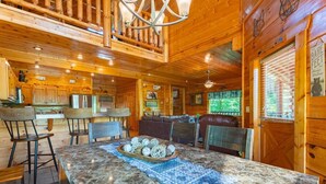 Interior de una cabaña de madera con comedor, cocina y zona de estar.