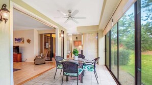 Um quarto amplo com área de jantar, ventilador de teto e janelas grandes com vista para o exterior.