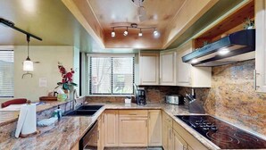 Una cocina con encimeras de granito, estufa integrada y armarios de madera.
