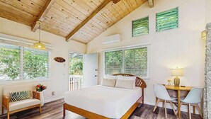 A bedroom with a wooden bed, a desk with chairs, and large windows with blinds. - NEW Kona Family Home and Ohana with Bay Sunsets (Kailua-Kona)
