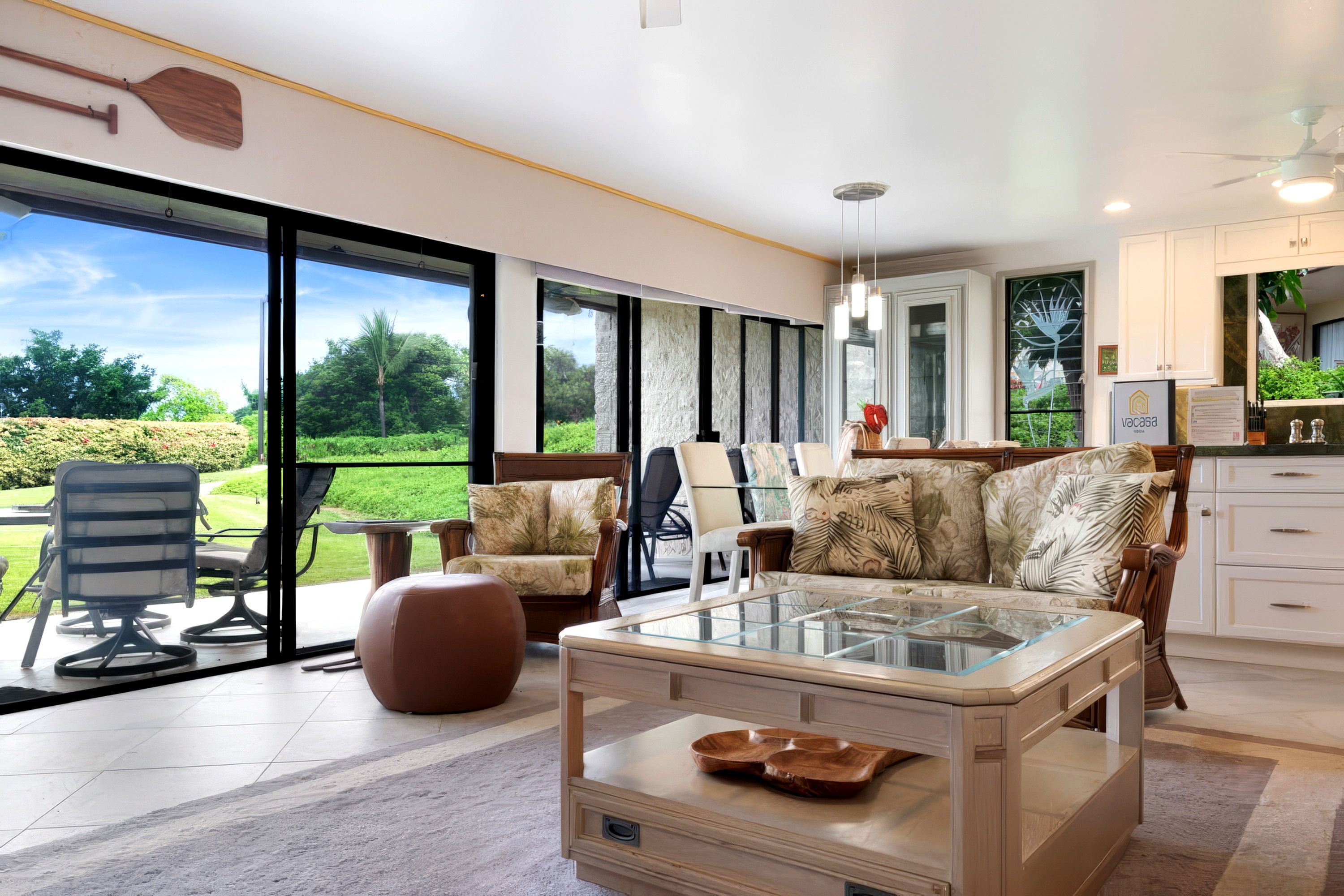 Un vaste espace de vie agrémenté d’une table basse en verre, de sièges confortables et offrant une vue sur un jardin luxuriant grâce à de grandes portes coulissantes.