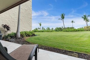 A patio with a bench, a well-maintained lawn, and palm trees. - Keauhou Punahele Golf/Beach Condo - Pool, Hot Tub, WIFI, Kitchen, BBQ, Laundry (Kailua-Kona)