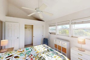 Ein Schlafzimmer mit Bett, Deckenventilator, Heizkörper, Fenster mit Jalousien und einer Tür.