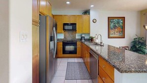 A kitchen with wooden cabinets, a stainless steel refrigerator, a microwave, a stove, and a sink. - *NEW* Fall Sale Two Lanais on the Fairway at Waikoloa Colony Villas (Waikoloa Village)