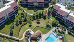 Vista aérea de un hotel con piscina central, varias construcciones y jardines ajardinados.
