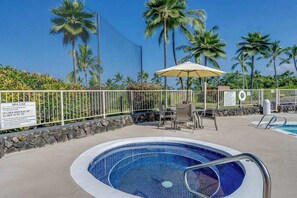 A swimming pool with a tiled edge, surrounded by a white fence, palm trees, and a sign indicating spa use. - Keauhou Golf View Condo- Pool, Hot Tub, Kitchen, Laundry, BBQ, Lanai, Near Beach (Kailua-Kona)