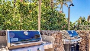 Two Weber gas grills set against a stone wall with lush greenery and a clear sky in the background. - *NEW* Fall Sale Garden-Level Fairway Stay by Kings' Shops and A-Bay (Waikoloa)