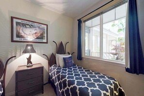 A bedroom with a bed, a nightstand, a lamp, a framed picture on the wall, and a window with curtains. - *NEW* Fall Sale Garden-Level Fairway Stay by Kings' Shops and A-Bay (Waikoloa)
