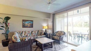 A living room with a sofa, armchair, coffee table, and a ceiling fan. - *NEW* Fall Sale Garden-Level Fairway Stay by Kings' Shops and A-Bay (Waikoloa)
