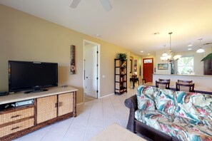 A living room with a television, a sofa, and a dining area with chairs. - *NEW* Fall Sale Garden-Level Fairway Stay by Kings' Shops and A-Bay (Waikoloa)