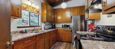 A kitchen with wooden cabinets, a stainless steel refrigerator, a microwave, and a stove.