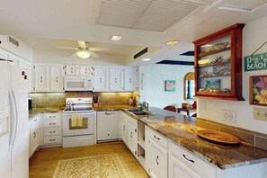 A kitchen with white cabinets, a microwave, an oven, a sink, and a ceiling fan. - *NEW* Top Floor Kona Coast Views for a Family of Four (Kailua-Kona)