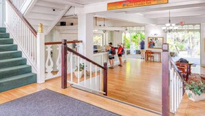 Hotellin aula, jossa on portaikko, vastaanottotiski ja kyltti, jossa toivotetaan vieraat tervetulleiksi Kona Island Inn -hotelliin.