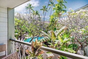 Een balkon met uitzicht op tropische begroeiing en een zwembad.