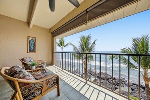 A balcony with wicker furniture, a potted plant, and a view of the beach and ocean. - Oceanfront View Kona Bali Kai 403-Pool, Hot Tub, Laundry, WIFI-Magic Sands Beach (Kailua-Kona)