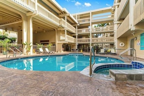 A swimming pool with a sun terrace, lounge chairs, and a multi-level building with balconies. - Oceanfront View Kona Bali Kai 403-Pool, Hot Tub, Laundry, WIFI-Magic Sands Beach (Kailua-Kona)