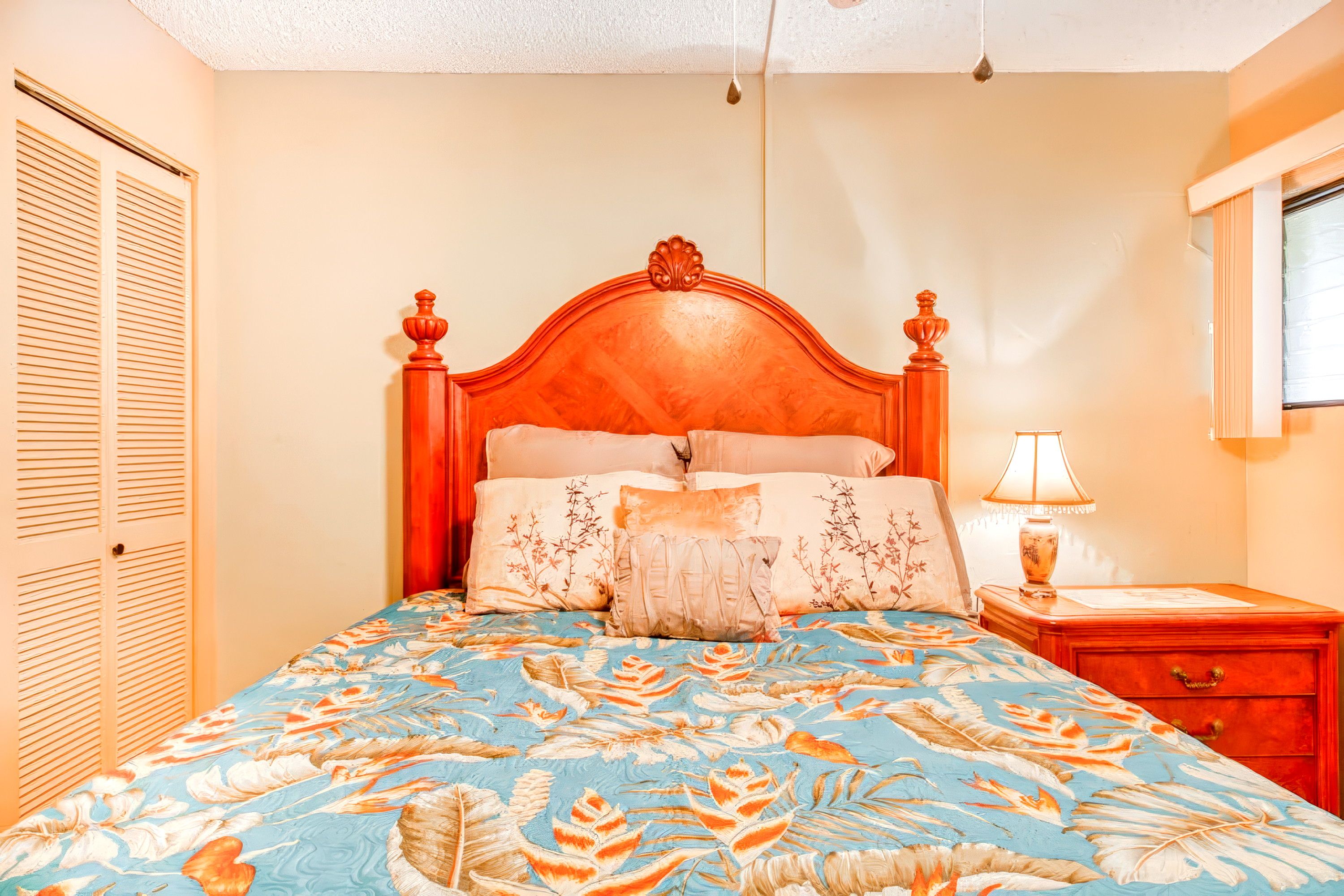 A bedroom with a bed, a nightstand, a lamp, and a window.
