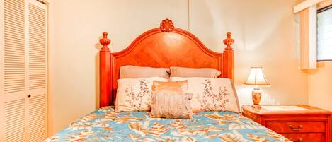 A bedroom with a bed, a nightstand, a lamp, and a window.
