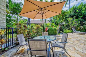 A patio with a round glass table, four chairs, and a large umbrella. - New Third-Floor Kona Views, Walk to Pier and Market (Kailua-Kona)