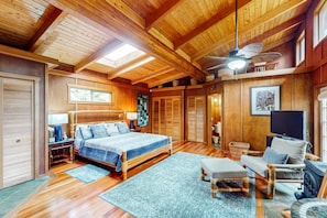 A wooden interior with a bed, a TV, and a fireplace. - NEW Five Rainforest Acres and a Wood-Burning Fire in Volcano NUC 19-0957 (Volcano)