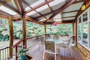 A wooden deck with a glass enclosure, surrounded by lush greenery. - NEW Five Rainforest Acres and a Wood-Burning Fire in Volcano NUC 19-0957 (Volcano)
