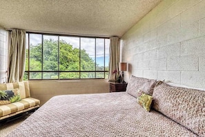 A bedroom with a large window, a bed, a sofa, and a nightstand. - Tropical Hilo Maunaloa Shores Condo w/ Pool - Walk to Beach, Shops, and Dining (Hilo)