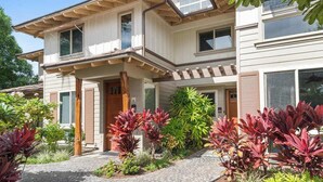 A two-story house with a covered porch, large windows, and a well-maintained garden with various plants. - *New* Fall Sale Mauna Lani Condo Near Beach Path with Waterfall Pool and Tennis (Kamuela)
