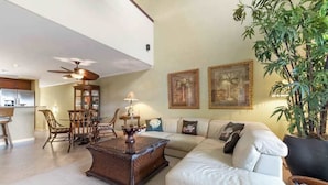 A living room with a sofa, coffee table, dining table, chairs, and a ceiling fan. - *New* Fall Sale Mauna Lani Condo Near Beach Path with Waterfall Pool and Tennis (Kamuela)