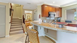 A kitchen with a central island, wooden cabinets, and a microwave. - *New* Fall Sale Mauna Lani Condo Near Beach Path with Waterfall Pool and Tennis (Kamuela)