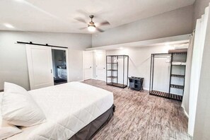 Ein Schlafzimmer mit Bett, Deckenventilator, Kleiderschrank und Einbauschränken.