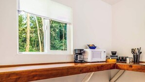 Eine Küche mit Fenster, einer Kaffeemaschine, einer Mikrowelle und Geschirr auf der Arbeitsfläche.