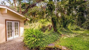 Ein Haus mit einer Veranda, ein kleiner Garten mit verschiedenen Pflanzen und einer Steinsäule.