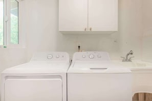 A laundry room with two white front-loading washing machines and a sink. - *NEW* Pahoa Family Home for 31-Night Puna Stays (Pahoa)