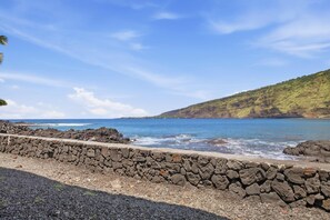A coastal landscape with a stone wall, clear blue sky, and calm sea. - *NEW* Kealakekua Bay Oceanfront Home with Views from Every Room (Captain Cook)