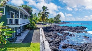 A beachfront property with a covered patio, outdoor seating, and a view of the ocean.